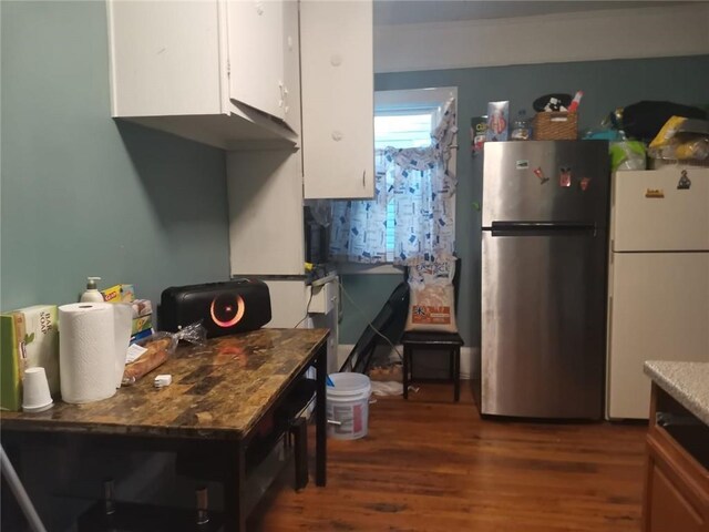 kitchen with stainless steel refrigerator, white refrigerator, dark hardwood / wood-style flooring, dark stone counters, and white cabinets