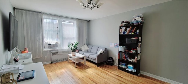 living area featuring wood-type flooring, radiator heating unit, and a notable chandelier