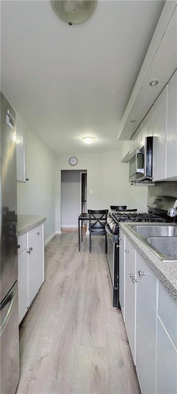 kitchen featuring white cabinetry, sink, light wood-type flooring, and appliances with stainless steel finishes