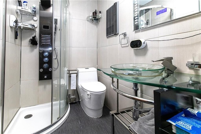 full bath featuring tile patterned flooring, toilet, a sink, tile walls, and a shower stall