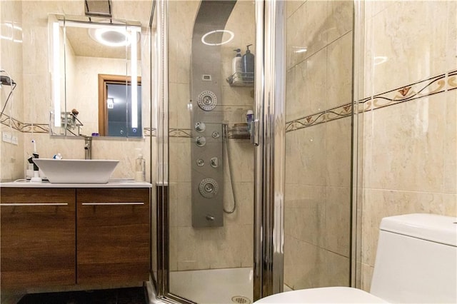 bathroom featuring toilet, vanity, tile walls, and a shower stall