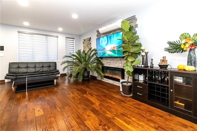 interior space featuring baseboards, dark wood-style floors, an AC wall unit, a stone fireplace, and recessed lighting