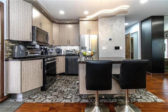 kitchen featuring dishwasher, stainless steel fridge with ice dispenser, dark countertops, range with gas cooktop, and a center island