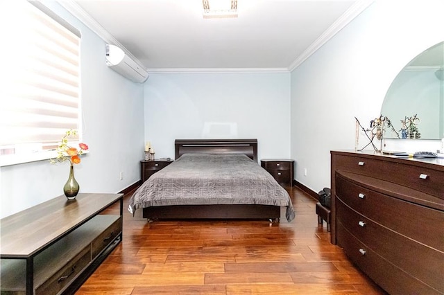 bedroom featuring a wall unit AC, light wood finished floors, baseboards, and ornamental molding