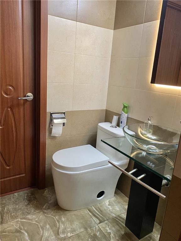 bathroom featuring sink, tile walls, and toilet