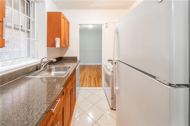 kitchen featuring white appliances, a sink, brown cabinets, and light tile patterned floors