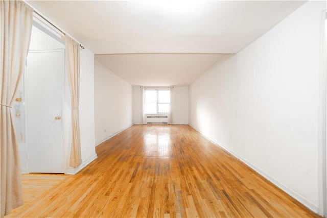 unfurnished room with light wood-style flooring, radiator heating unit, and baseboards