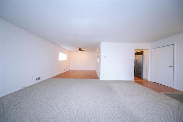 unfurnished room with light colored carpet and ceiling fan