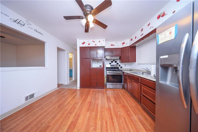 kitchen with ceiling fan, appliances with stainless steel finishes, sink, and light wood-type flooring