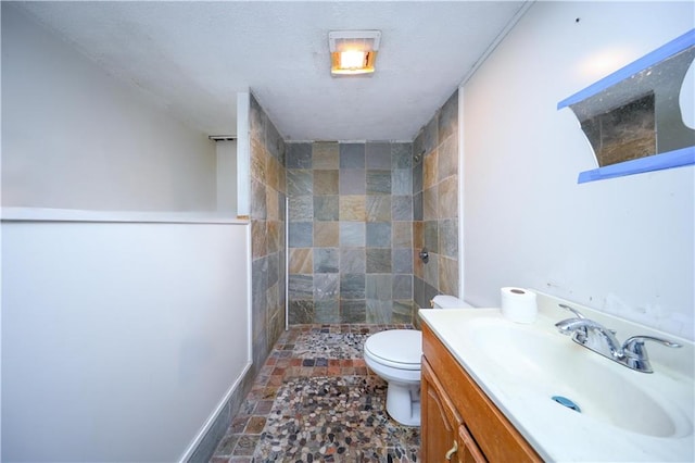 bathroom with vanity, toilet, and tiled shower