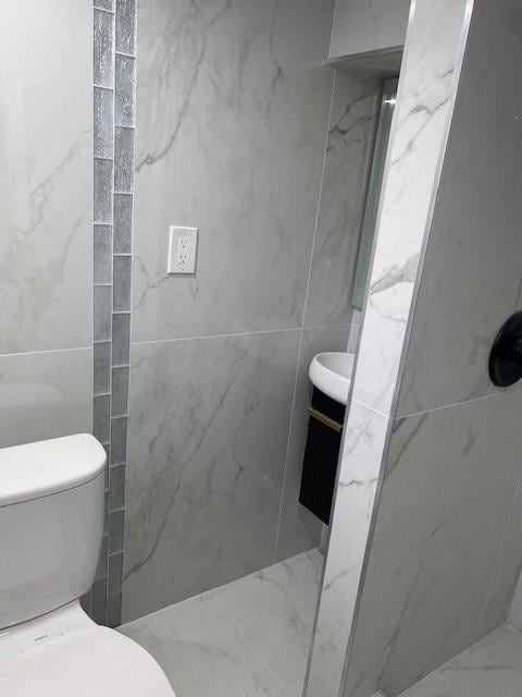298 Bay 14th St, Brooklyn, NY 11214 - bathroom featuring tile walls, toilet, a marble finish shower, and vanity