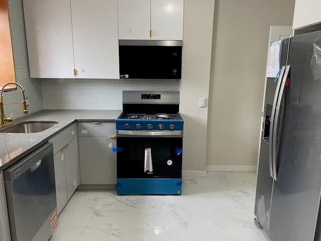 kitchen with stainless steel appliances, a sink, marble finish floor, gray cabinets, and decorative backsplash