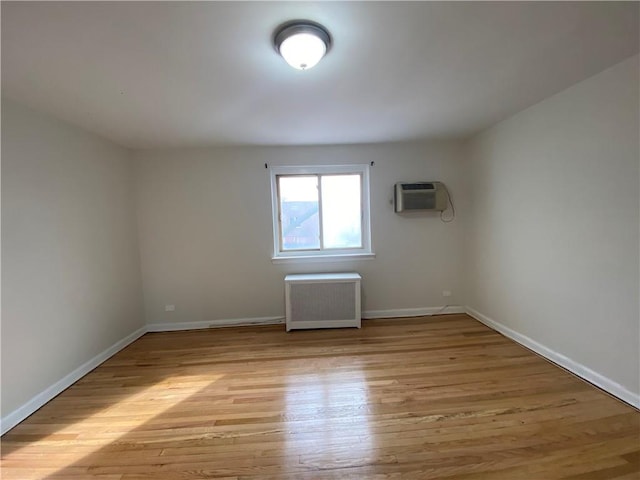 298 Bay 14th St, Brooklyn, NY 11214 - empty room with radiator, a wall mounted air conditioner, light wood finished floors, and baseboards