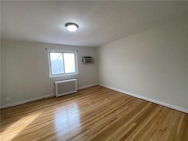 spare room featuring light wood-type flooring, radiator, and baseboards