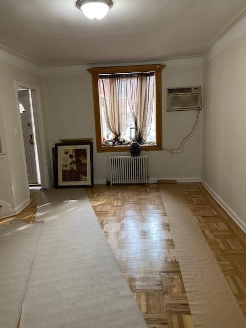 298 Bay 14th St, Brooklyn, NY 11214 - empty room with radiator heating unit, a wall unit AC, baseboards, and ornamental molding