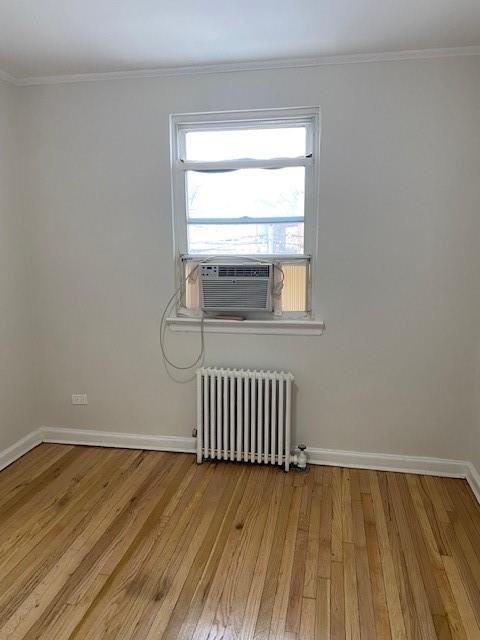 298 Bay 14th St, Brooklyn, NY 11214 - spare room featuring radiator, wood finished floors, baseboards, cooling unit, and crown molding