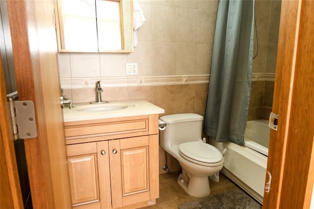 bathroom with toilet, tile patterned floors, shower / bath combo with shower curtain, vanity, and tile walls