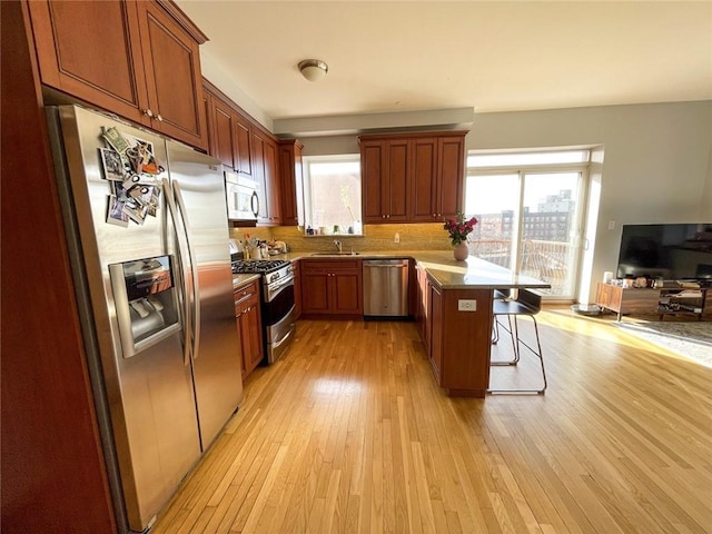 kitchen with stainless steel appliances, a breakfast bar, a sink, open floor plan, and a center island