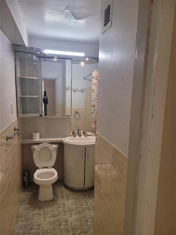 bathroom with vanity, toilet, and tile walls