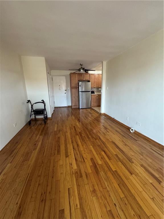 unfurnished living room with ceiling fan and dark wood-type flooring