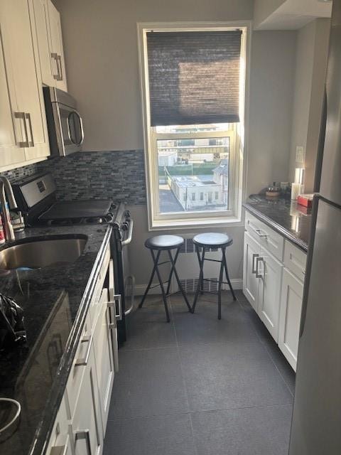 393 Avenue S Unit 5H, Brooklyn, NY 11223 - kitchen featuring dark stone countertops, stainless steel appliances, white cabinets, backsplash, and a sink