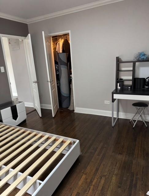 bedroom featuring a closet, ornamental molding, baseboards, and wood finished floors