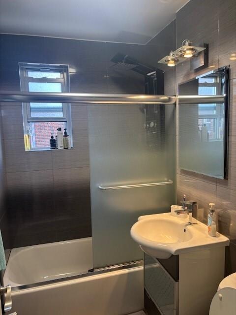 full bathroom with toilet, vanity, shower / bath combination with glass door, and tile walls