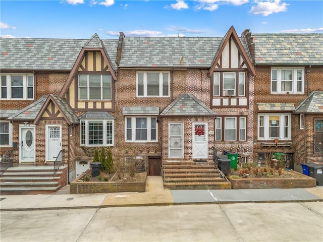 view of front facade featuring entry steps, a high end roof, and brick siding