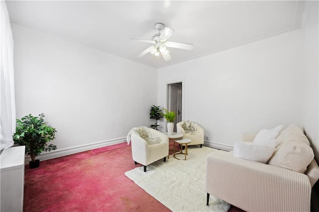 sitting room featuring carpet, baseboards, and ceiling fan