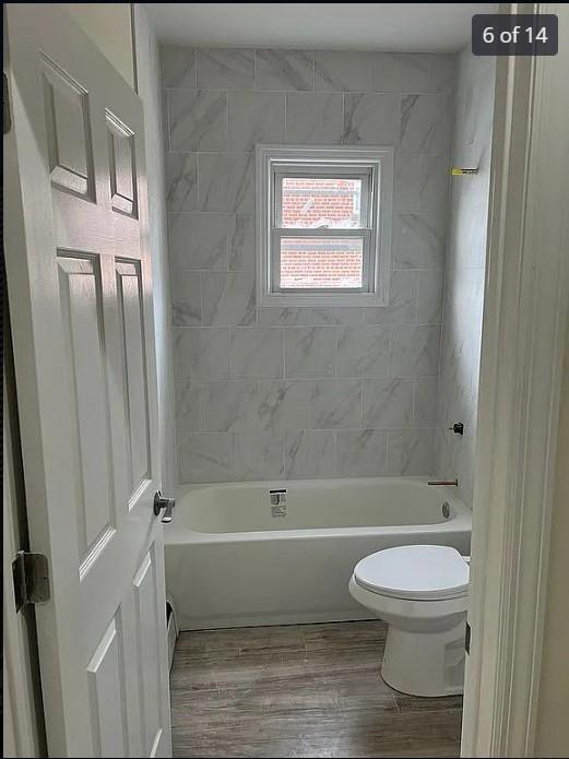 bathroom featuring hardwood / wood-style floors, tiled shower / bath combo, and toilet