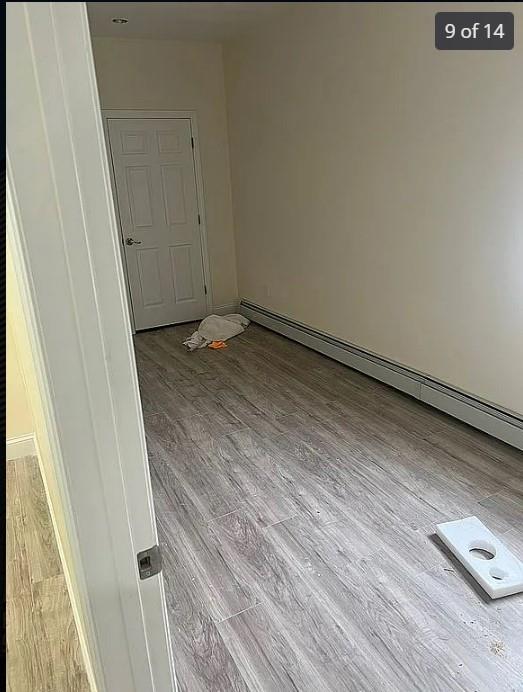 spare room featuring a baseboard radiator and light hardwood / wood-style flooring