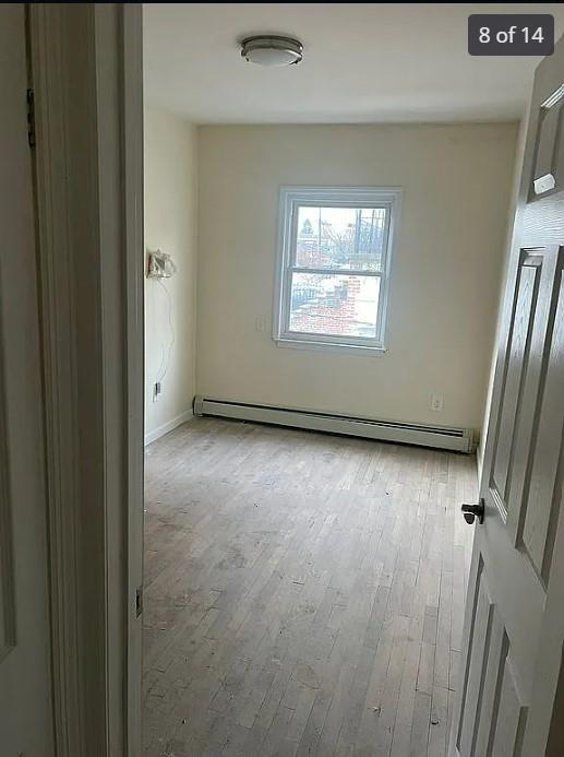 empty room featuring baseboard heating and light hardwood / wood-style flooring