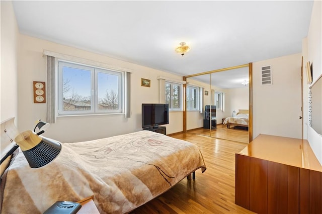 bedroom with visible vents, wood finished floors, and a closet