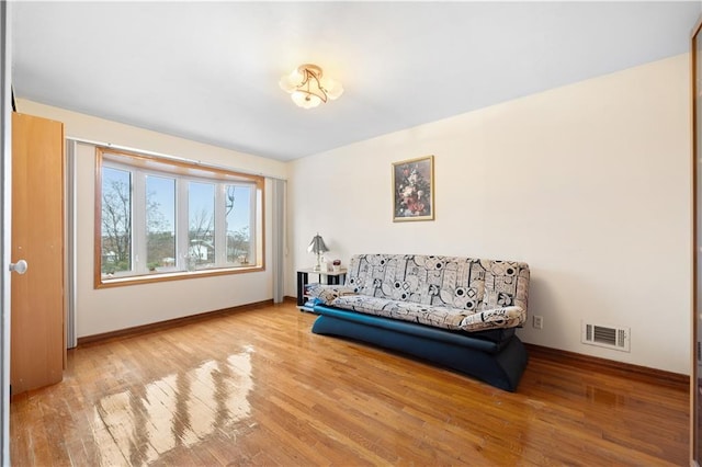 living area with visible vents, wood finished floors, and baseboards