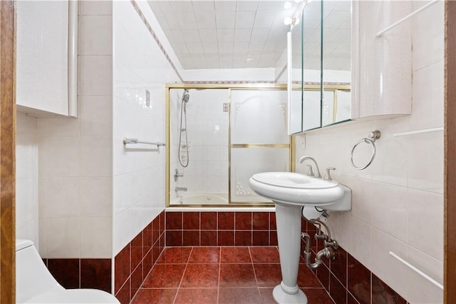 full bath with tile walls, tiled shower / bath combo, toilet, and tile patterned flooring