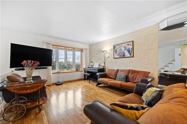 living room featuring wood finished floors, baseboards, and stairs