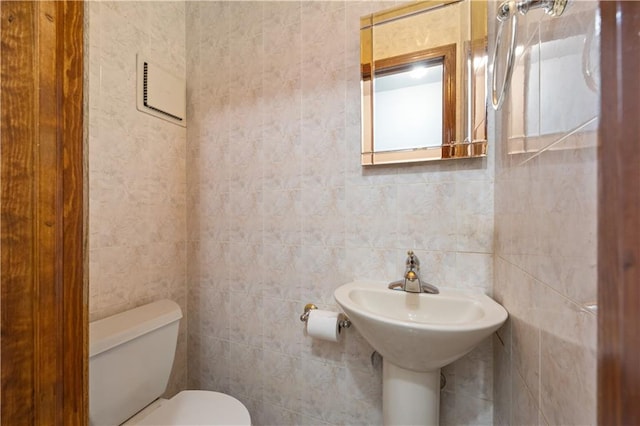 half bathroom with toilet and tile walls