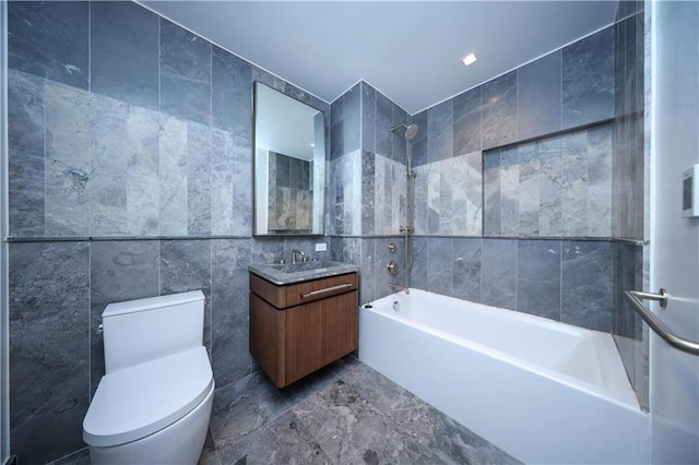 bathroom with tile walls, vanity, toilet, and shower / bathtub combination