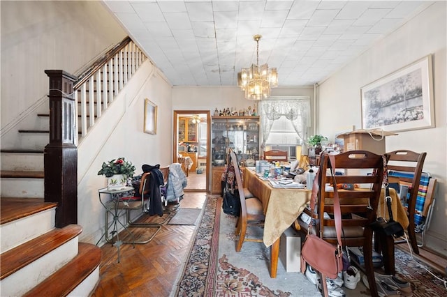 dining space with parquet flooring and a chandelier