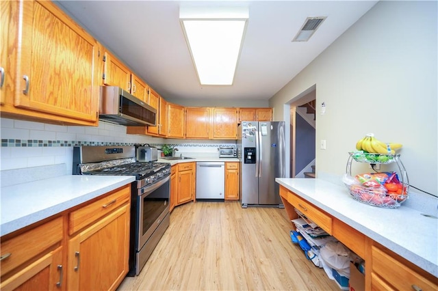 kitchen with light wood-type flooring, visible vents, stainless steel appliances, and light countertops