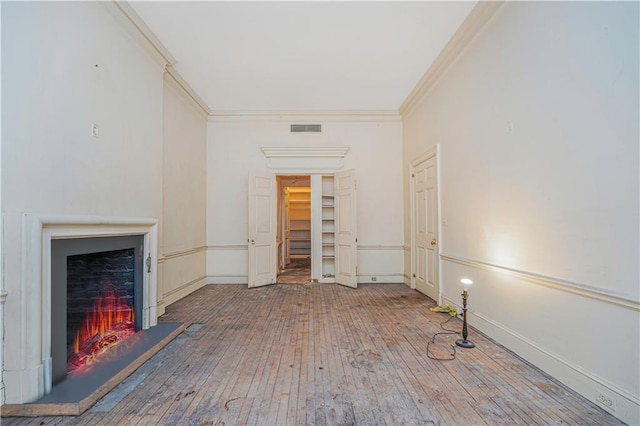 unfurnished living room with hardwood / wood-style flooring and ornamental molding