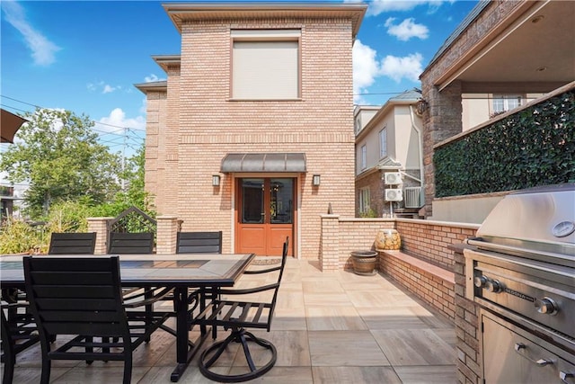 view of patio with french doors, outdoor dining area, an outdoor kitchen, and a grill