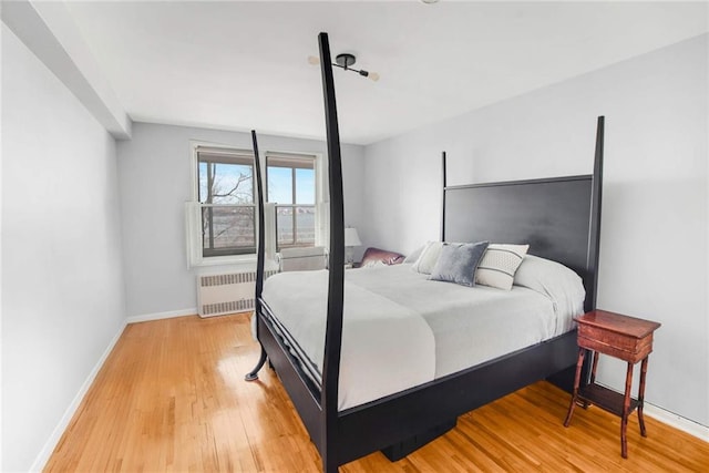 bedroom featuring light wood finished floors, radiator heating unit, and baseboards