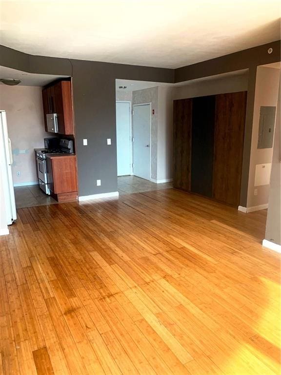 unfurnished living room featuring baseboards and light wood finished floors