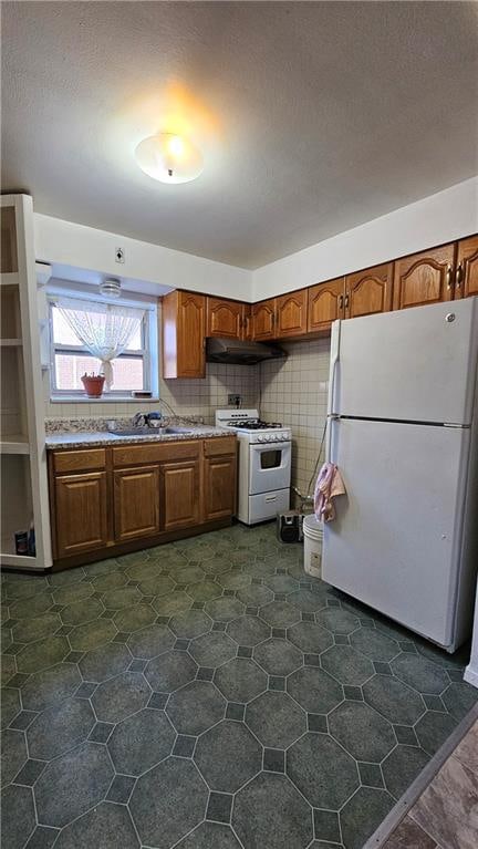 kitchen with sink, a textured ceiling, backsplash, and white appliances