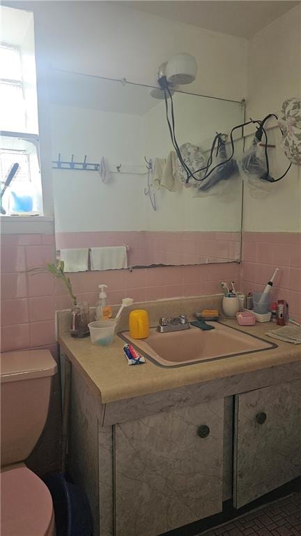 bathroom with toilet, sink, and tile walls