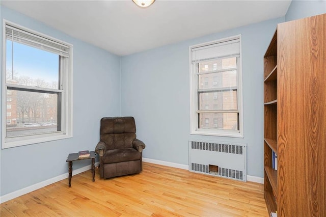 sitting room featuring radiator heating unit, baseboards, and wood finished floors