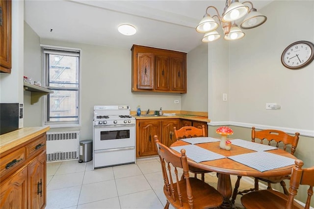 kitchen featuring radiator, white gas stove, brown cabinetry, a chandelier, and light countertops