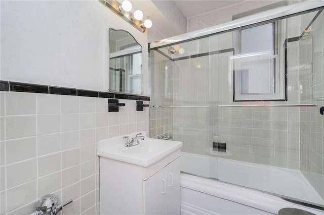 full bath with vanity, tile walls, and bath / shower combo with glass door