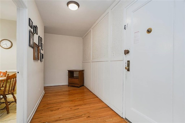 hall with light wood-style floors and a wainscoted wall